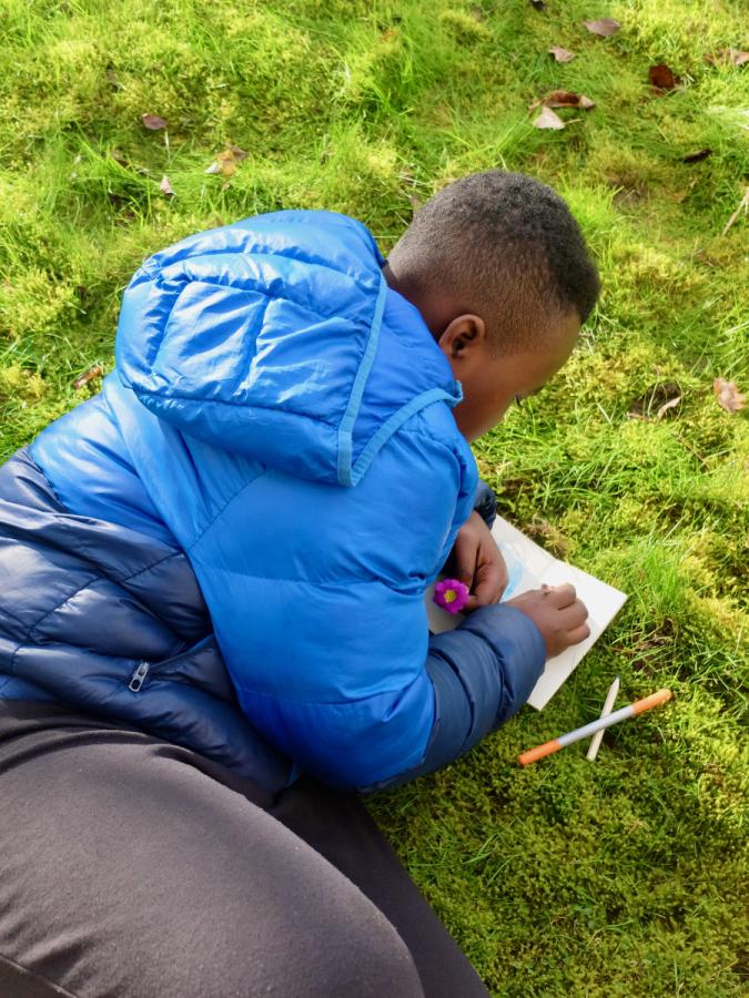 Boy in blue coat drawing flower